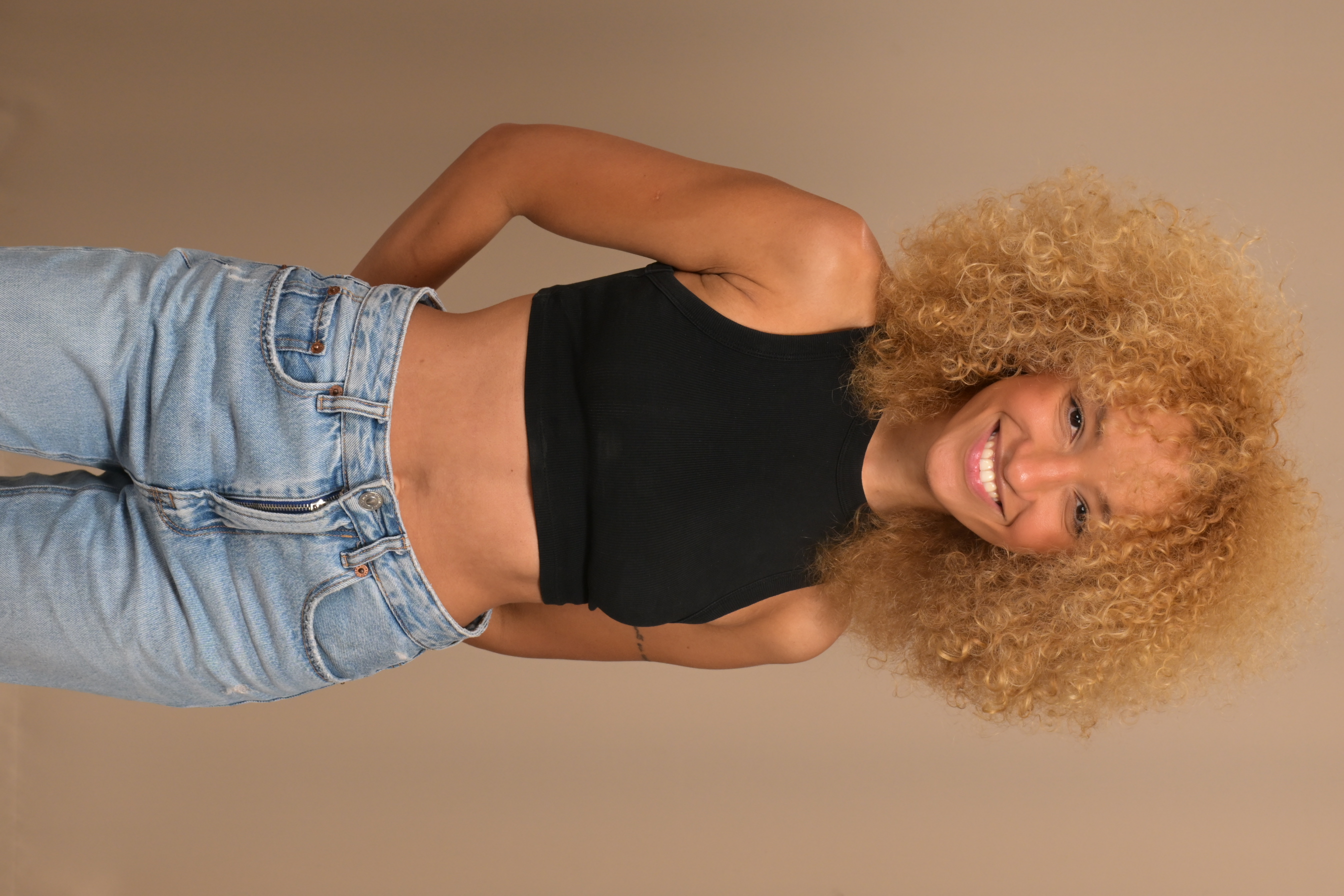 Smiling full-length portrait of Nalu wearing a black top and jeans.
