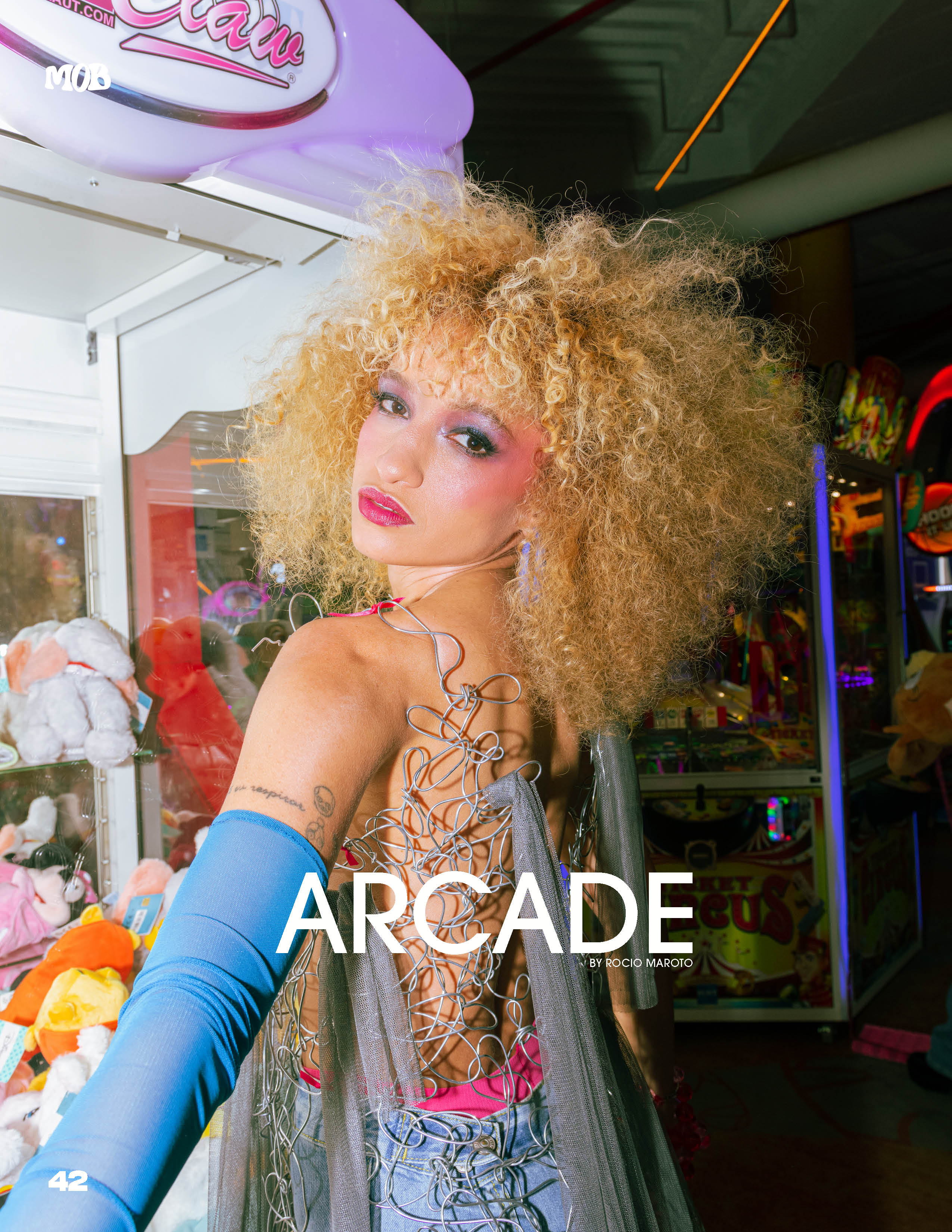Nalu Rodrigues in a cobalt-blue top among arcade machines, photographed by Rocío Maroto.
