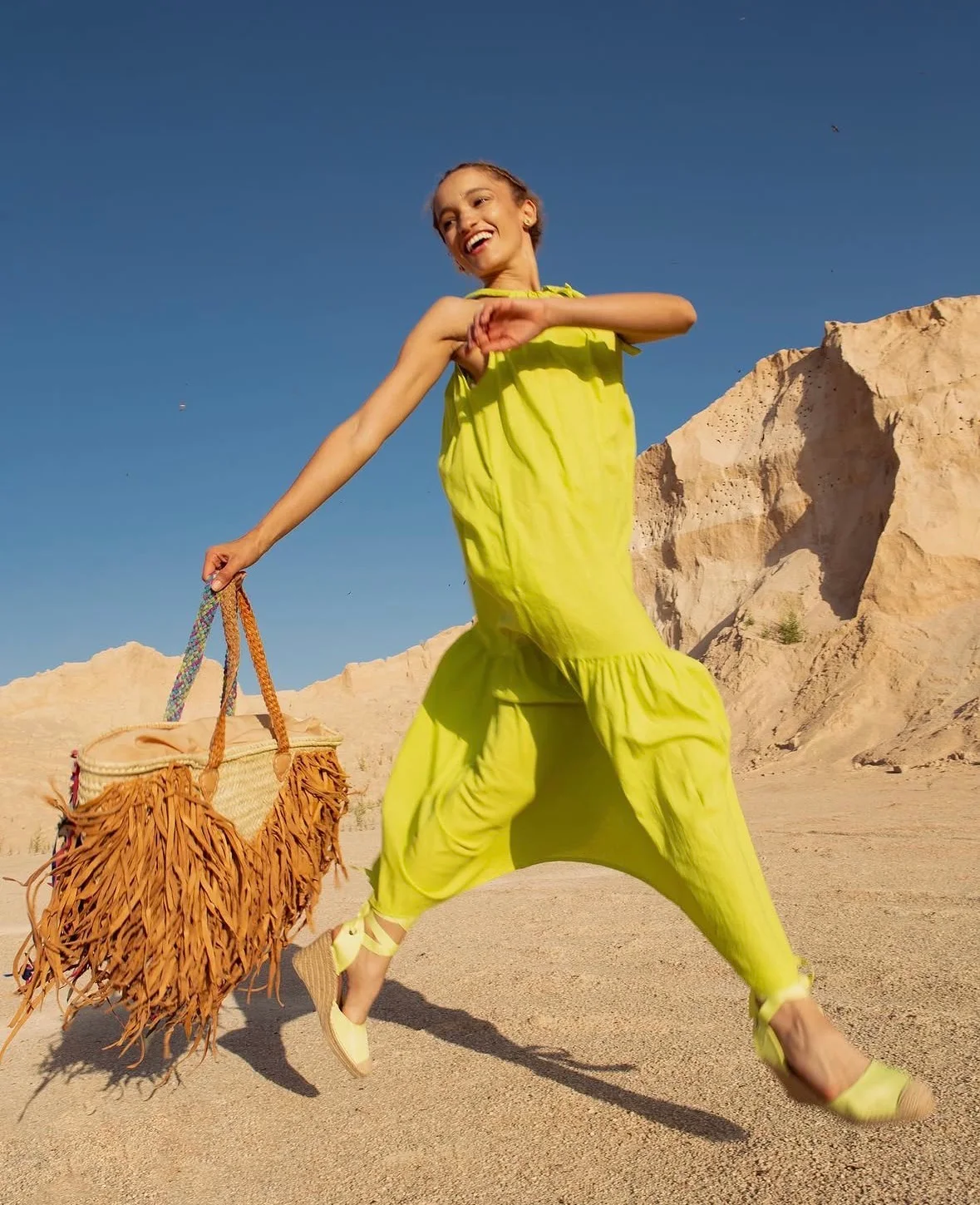 Nalu posing in a lime-green look against a rocky landscape.